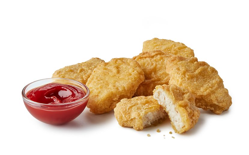 Side view of 6 checken nuggets with a small bowl of ketchup sauce.